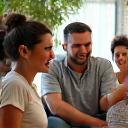 Group of diverse adults smiling and engaging in conversation, illustrating a supportive community.